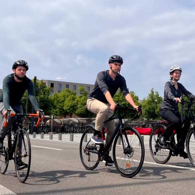 Three cyclists are riding side by side on the road.