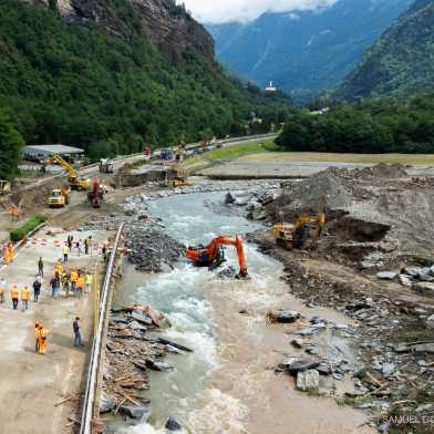 After a landslide, the highway is cleared next to a river in a valley