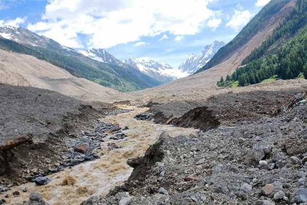 Debris has accumulated on the valley floor, and the course of the Lonza can be seen winding its way through it.