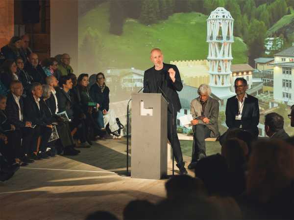 Benjamin Dillenburger stands at the lectern, surrounded by listeners.