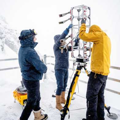 Drei Personen installieren eine Antenne.