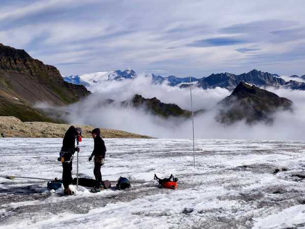 zwei Personen auf einem Gletscher beim Bohren