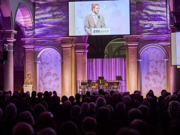 Nic Cantieni steht auf der Bühne im Hauptgebäude der ETH Zürich und spricht zum Publikum.