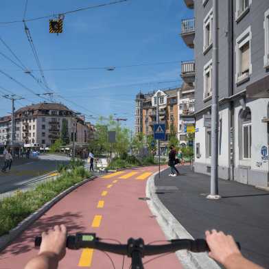Aus der Perspektive eines Fahrradfahrers. Sie können einen zweispurigen Radweg sehen. Er ist durch ein Blumenbeet von der Straße getrennt.